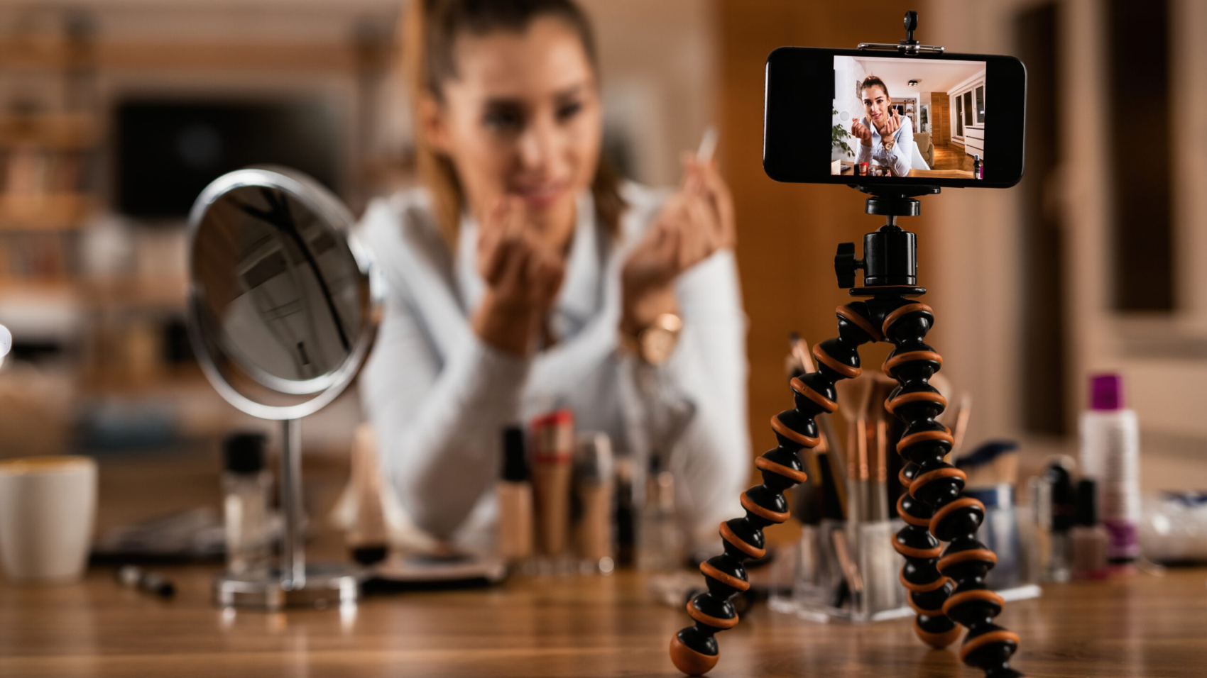 Close-up of female influencer live streaming about beauty products at home.