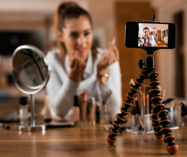 Close-up of female influencer live streaming about beauty products at home.