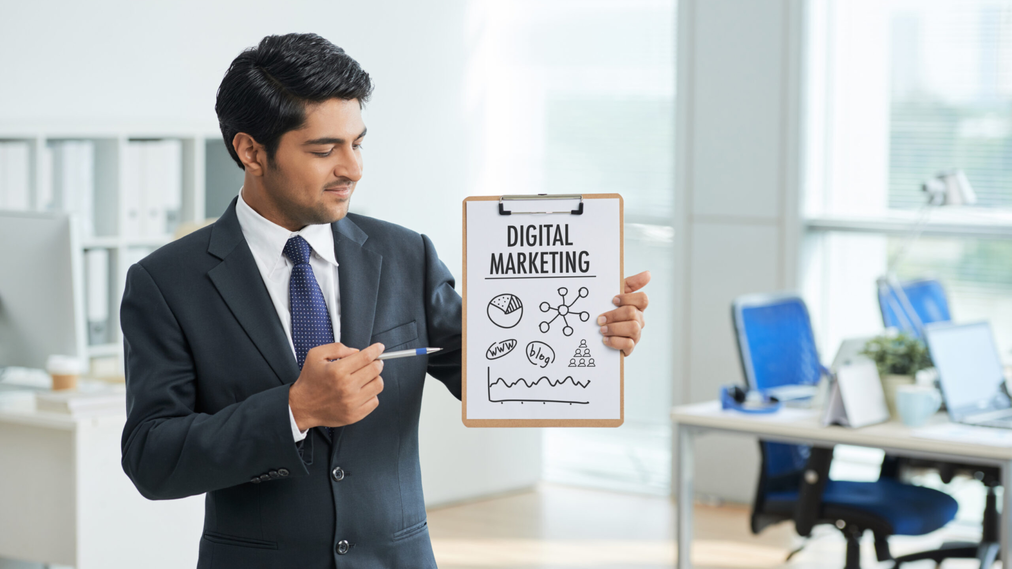 man-suit-standing-office-with-clipboard-pointing-poster-with-words